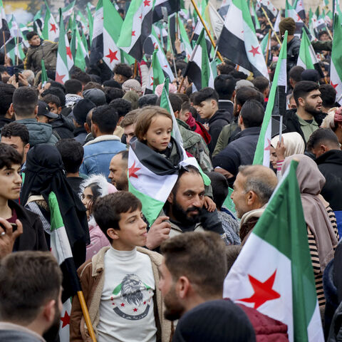 Thousands of people wave Syrian flags as they gather in a square during an anniversary rally in Idlib, Syria, on Dec. 8, 2025. (Photo by Omar Albaw/Middle East Images/AFP via Getty Images)
