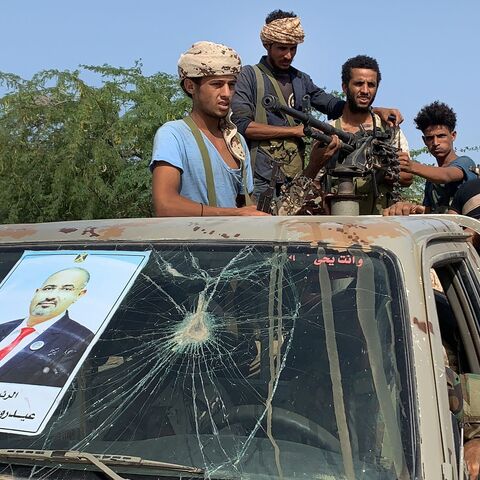 Fighters loyal to Yemen's Southern Transitional Council separatists stand in the back of a pickup struck, bearing the portrait of STC Chief Aidarus al-Zubaidi