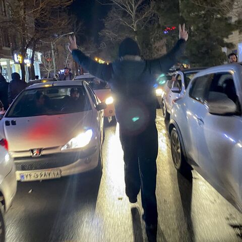 A protester flashes victory signs as traffic slows during demonstrations in Hamedan, Iran, on Jan. 1, 2026. 