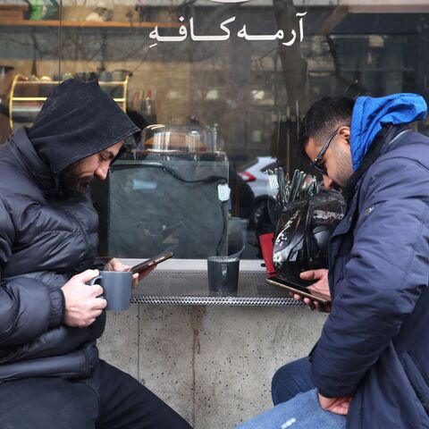 Men use their mobile phones while sitting at a coffee shop in Tehran, on Jan. 7, 2026.