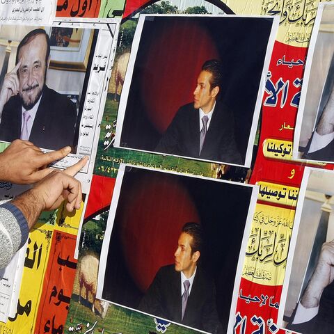 A member of the Alawite community pastes on a wall, in the northern Lebanese city of Tripoli , on December 6, 2007, pictures of Syrian opposition leader Rifaat al-Assad (R) and his son Ribal. 