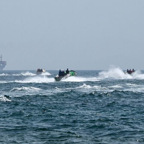Small boats loaded with merchandise sail past the St Kitt's and Nevis-flagged container ship Marsa Victory in the waters of the Strait of Hormuz off the coast of Khasab in the northern Musandam Peninsula, Oman, June 25, 2025.