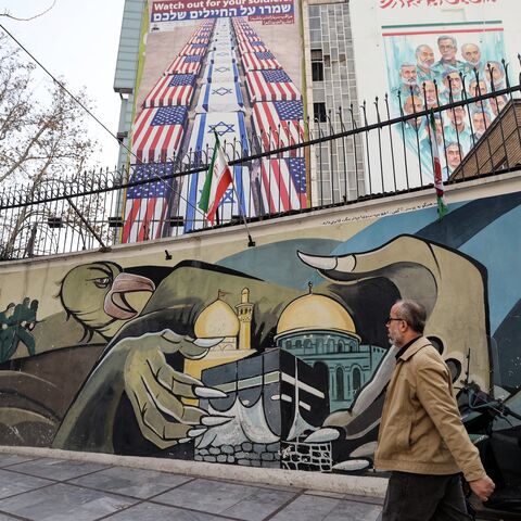 An Iranian man walks past an anti-US and anti-Israel banner hanging on a building in Palestine Square in Tehran on Jan. 27, 2026.