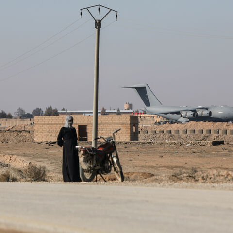 A person with a motorbike stands on the side of a road as US-led coalition plane operates at a base on Jan. 26, 2026 in Al-Shaddadi, Syria. 
