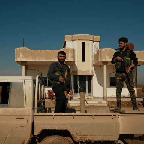 Syrian Democratic Forces fighters stand on a pick-up truck to provide security during an inspection of SDF positions on the Tell Brak frontline in Syria on Jan. 26, 2026.