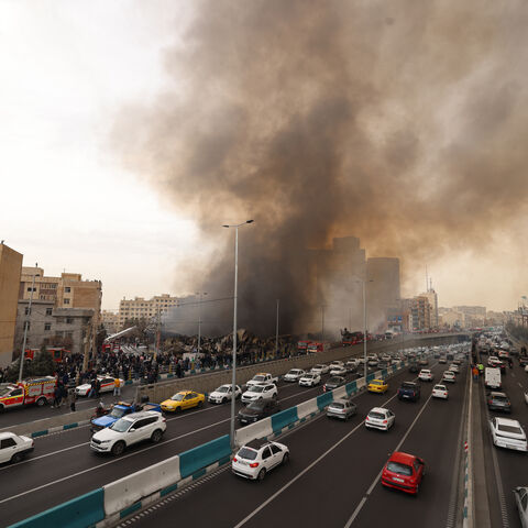 Motorists drive past as firefighters battle a fire that broke out in Jannat Bazaar, west of Tehran on Feb. 3, 2026. 