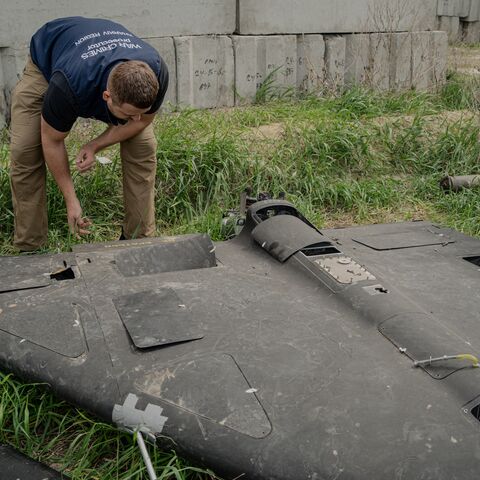 Dmytro Chubenko, spokesperson of the Kharkiv prosecutor, and his assistant look at a Russian Shahed drone shot down by Ukraine's air defense forces in a field used for the storage of Russian missiles in Kharkiv, on April 30, 2025.