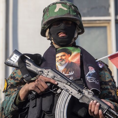 A security forces member with a picture of Iran's new supreme leader, Ayatollah Mojtaba Khamenei, watches over demonstrators as they gather for a rally in support of the new supreme leader at Enghelab Square on March 9, 2026 in Tehran, Iran. 