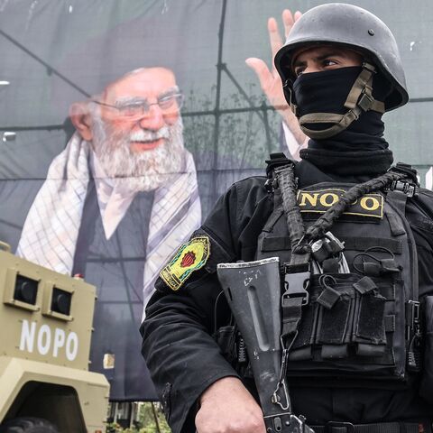 A member of the Iranian security forces stands guard next to a banner honoring Iran's slain supreme leader, Ayatollah Ali Khamenei, in Tehran on March 31, 2026. 
