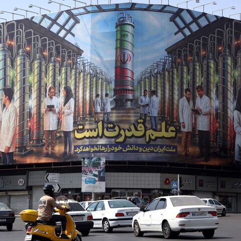 Iranians drive next to a billboard displaying pictures of nuclear scientists, centrifuges and a sentence reading in Farsi "Science is the power," at Enqelab Square in Tehran, on Aug. 29, 2025. 