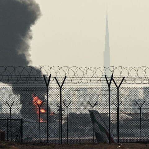 The Dubai skyline with the landmark Burj Khalifa skyscraper (R) is pictured as a smoke plume rises from an ongoing fire near Dubai International Airport on March 16, 2026. Flights were gradually resuming at Dubai airport on March 16, previously the world's busiest for international flights, the airport operator said, after a "drone-related incident" sparked a fuel tank fire nearby, as Iran kept up its Gulf attacks. (Photo by AFP via Getty Images) /