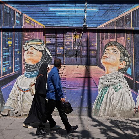 People walk past a wall mural along the roadside in Tehran on April 12, 2026.