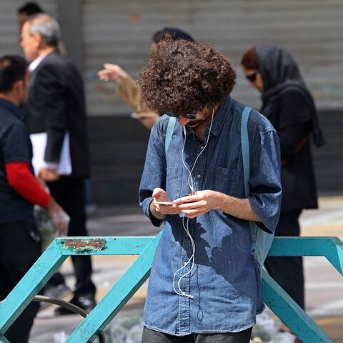 A man uses his mobile phone while standing at the Valiasr Square in Tehran on April 19, 2026. — ATTA KENARE / AFP via Getty Images