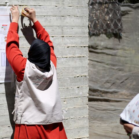 An elections employee tapes a poster with instructions to voters ahead of the upcoming municipal elections in Deir al-Balah in the central Gaza Strip on April 21, 2026.