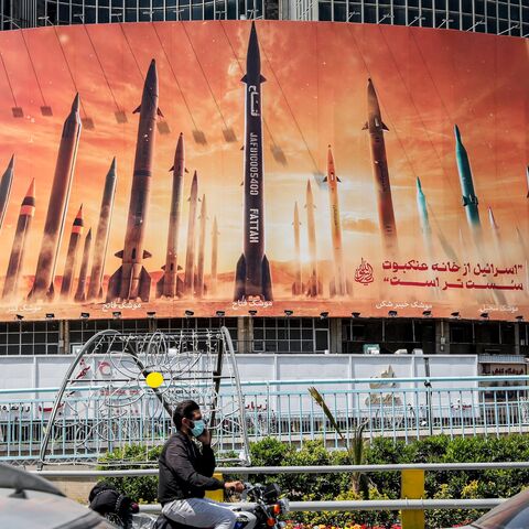 Traffic passes a billboard depicting Iranian ballistic missiles in service, with text in Arabic reading "the honest [person's] promise" and in Persian "Israel is weaker than a spider's web," Valiasr Square, Tehran, April 15, 2024. ATTA KENARE/AFP via Getty Images.
