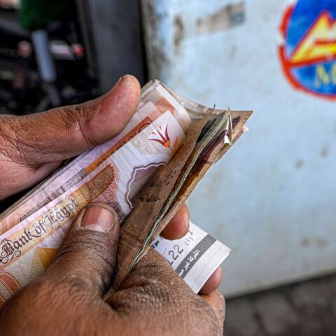 A worker counts banknotes after filling up the tank of a vehicle at a petrol station in Giza on March 10, 2026.