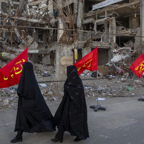 Women walk past buildings destroyed in a joint attack by Israel and the United States on April 6, 2026, in Tehran, Iran. 