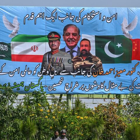 Motorcyclists ride past a billboard featuring Pakistan's Prime Minister Shehbaz Sharif (C) and Army Chief and Field Marshal Syed Asim Munir (L) in Islamabad on April 20, 2026, ahead of anticipated US-Iran peace talks. 