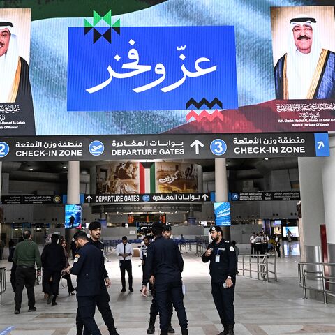Kuwaiti security officers stand beneath a screen displaying portraits of the Emir of Kuwait Sheikh Meshal al-Ahmad al-Jaber al-Sabah (R) and the Kuwaiti crown prince Sheikh Sabah al-Khaled al-Hamad al-Sabah, alongside the words "Pride and Glory", at Kuwait International Airport in Kuwait City on June 1, 2026, as the airport resumes operations following a phased reopening plan. 