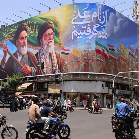 People ride motorcycles past a large billboard showing portraits of Iran's late supreme leader, Ayatollah Ruhollah Khomeini (L), and slain supreme leader Ayatollah Ali Khamenei (R) in central Tehran on June 8, 2026. 