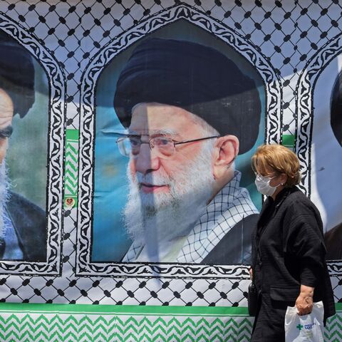 A woman walks past a banner bearing the images of the late founder of the Islamic Revolution supreme leader Ayatollah Ruhollah Khomeini (L).
