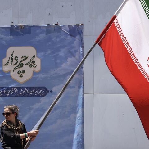 An Iranian woman waves a national flag at Valiasr Square in Tehran on June 15, 2026. 