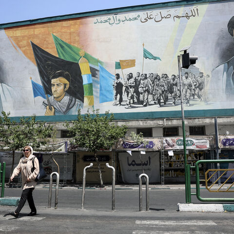 An Iranian woman walks past a mural depicting late Iranian supreme leaders Ayatollah Ali Khamenei (L) and Ayatollah Ruhollah Khomeini (R) in Tehran on June 18, 2026. 