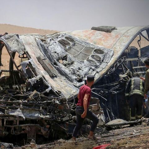 This handout picture taken and released by the official Syrian Arab News Agency (SANA) on July 25, 2026 shows people and first responders inspecting the damage at the scene of the collision of two passenger buses on the Damascus-Deir Ezzor road
