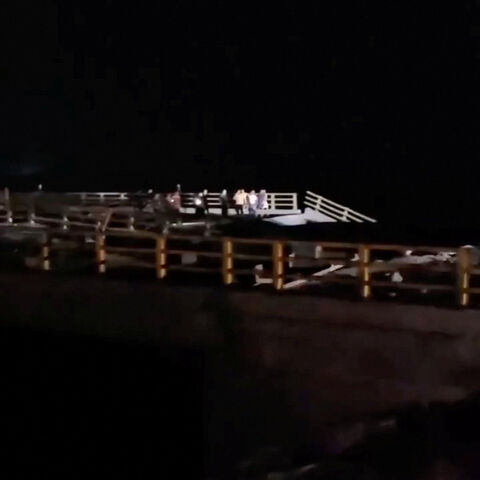 People stand near a damaged portion of a bridge in the aftermath of a strike, in Bandar Khamir, Hormozgan province, Iran July 16, 2026 in this screen grab obtained from social media video. Social Media/via REUTERS