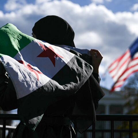 A man holds a Syrian flag across the street from the White House after Syrian President Ahmed al-Sharaa met with President Donald Trump at White House in Washington, on Nov. 10, 2025. 