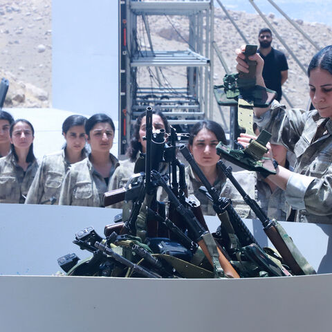 Fighters with the Kurdistan Workers' Party (PKK) line up to put their weapons into a pit during a ceremony in Sulaimaniyah, in Iraq's autonomous Kurdistan region, on July 11, 2025. 