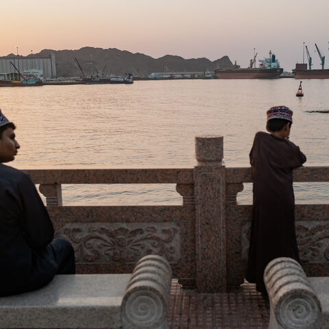 Two brothers watch oil tankers, general cargo ships, bulk carriers, and fishing boats anchored in the waters off Muscat near the Strait of Hormuz on June 18, 2026 in Muscat, Oman.