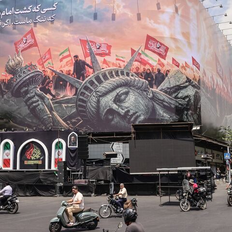 Iranians drive past an anti-US billboard at Enghelab Square in central Tehran, Aug. 3, 2026.