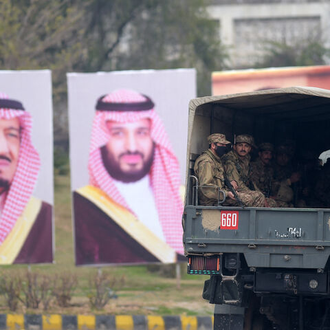 Pakistani soldiers (R) patrol on a street next to welcoming posters of Saudi Arabian Crown Prince Mohammed bin Salman in Islamabad on Feb. 17, 2019.