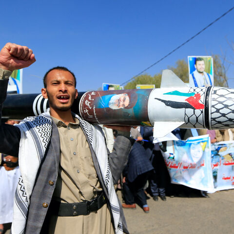 A Yemeni man holds up a mock missile decorated with the colors of the Palestinian flag and the chechered keffiyeh in front of portraits of slain Hamas leader Yahya Sinwar (L) and the leader of the Houthi movement, Abdel Malek al-Houthi (R), during a protest in Sanaa to denounce strikes on Yemen and Israel's bombardment of Gaza on Jan. 15, 2025. 