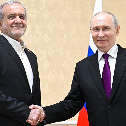 In this pool photograph distributed by the Russian state agency Sputnik, Russia's President Vladimir Putin and Iranian President Masoud Pezeshkian shake hands during a meeting in Turkmenbashi on Oct. 8, 2026.