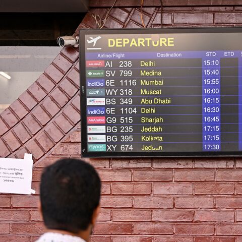 A man looks at a screen displaying the flight schedule at the Hazrat Shahjalal International Airport in Dhaka, on Oct. 12, 2026, as Saudi Arabia-bound flights remain canceled a day after a Houthi strike at Riyadh's international airport.