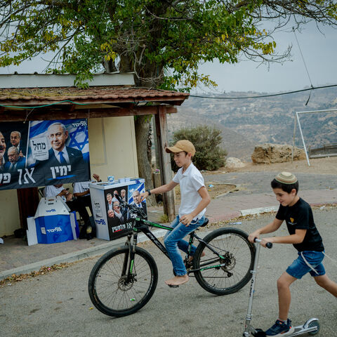 ADORA, WEST BANK - OCTOBER 27: Israeli children ride a bicycle and a scooter past an election campaign stand of Prime Minister Benjamin Netanyahu's Likud party on October 27, 2026 in the Israeli settlement of Adora, West Bank. Voting is underway to choose 120 members of the Knesset, which will determine the make-up of the government that succeeds incumbent Israeli Prime Minister Benjamin Netanyahu's right-wing coalition. Around 500,000 Israeli settlers living in the occupied West Bank and are entitled to ca