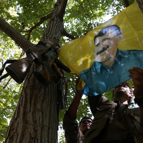 A member of the anti-Iranian group, Kurdistan Free Life Party (PJAK), hangs up a flag of jailed Kurdistan Workers' Party (PKK) leader, Abdullah Ocalan, at their base deep on the Iraq-Iran border of northern Iraq's Kurdish autonomous region, on August 28, 2017. / AFP PHOTO / SAFIN HAMED (Photo credit should read SAFIN HAMED/AFP/Getty Images)