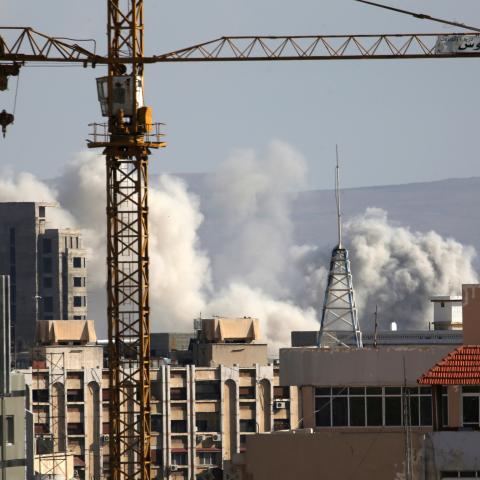 A construction crane is seen as smoke rises from Yarmouk Palestinian camp in Damascus, Syria April 21, 2018. REUTERS/Ali Hashisho - RC16C2D4AC60