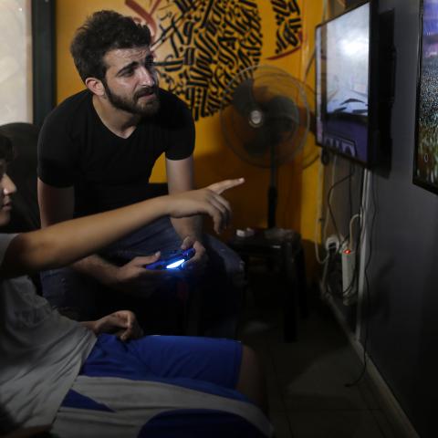 Palestinian rapper Ibrahim Ghunaim (MC Gaza) looks on as a child gestures, at his video game shop in Gaza City, August 16, 2017. REUTERS/Mohammed Salem  SEARCH "SALEM RAPPER" FOR THIS STORY. SEARCH "WIDER IMAGE" FOR ALL STORIES. - RC1123875E80