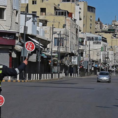 A policeman holds a stop sign in an almost deserted avenue in the Jordanian capital Amman, during a lockdown due to the coronavirus panemic, on February 26, 2021. (Photo by Khalil MAZRAAWI / AFP) (Photo by KHALIL MAZRAAWI/AFP via Getty Images)