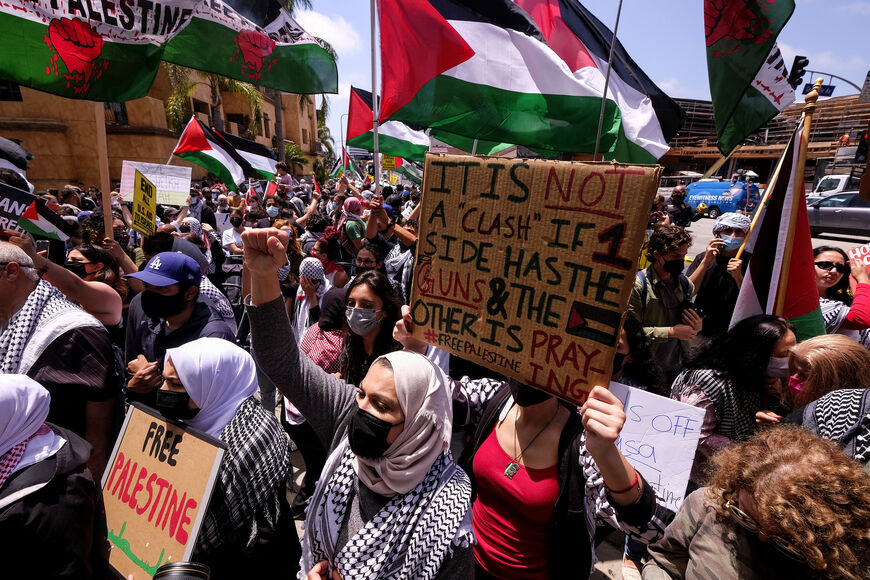 People hold up signs and wave Palestinian flags during a protest against Israel and in support of Palestinians outside the Israeli Consulate in Los Angeles, California, on May 11, 2021. - The UN Security Council will hold an urgent meeting on Wednesday over the deadly unrest playing out between Israel and the Palestinians, its second such session in three days, diplomatic sources said on May 11. (Photo by RINGO CHIU / AFP) (Photo by RINGO CHIU/AFP via Getty Images)