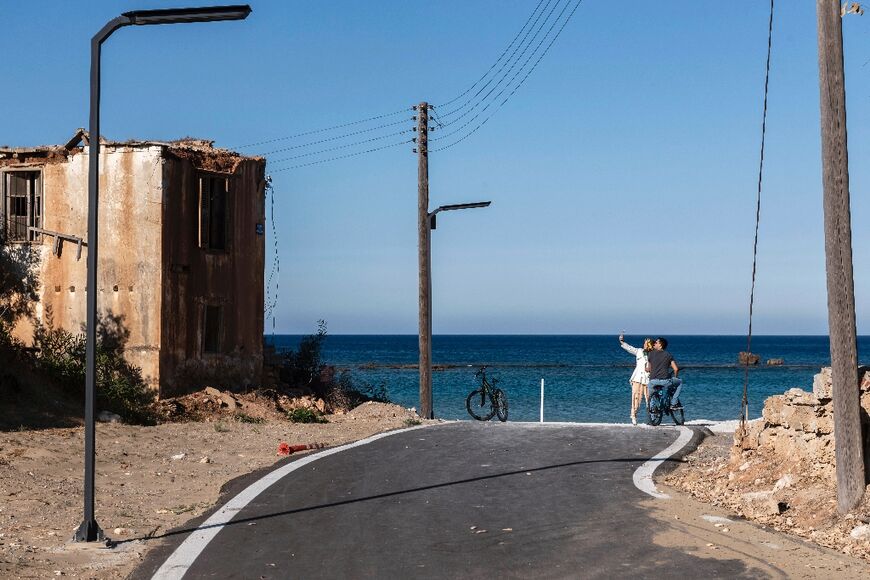 Tourists take selfies at the seaside in the fenced-off area of Varosha in Famagusta town in the self-proclaimed Turkish Republic of Northern Cyprus (TRNC) of the divided Mediterranean island of Cyprus