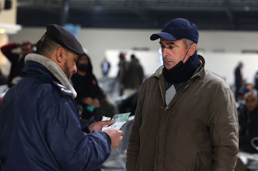 A Palestinian policeman checks the identity of a worker as he leaves Beit Hanun