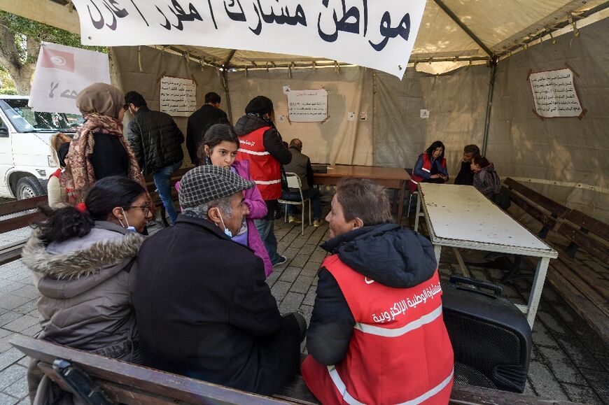 Tunisian volunteers explain to citizens how to fill out an online public poll, on March 14, 2022in the capital Tunis