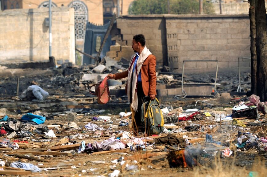 A man salvages some belongings following overnight air strikes by the Saudi-led coalition, targeting the Huthi rebel-held Yemeni capital Sanaa, on March 26, 2022, after the Iran-backed Huthi rebels fired on 16 targets across Saudi Arabia 