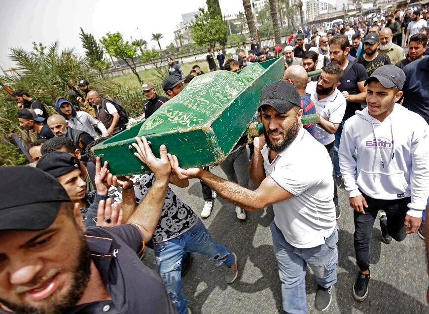 Mourners carry the body of a victim after a boat loaded with migrants capsized off the northern city of Tripoli, at a funeral on April 25, 2022