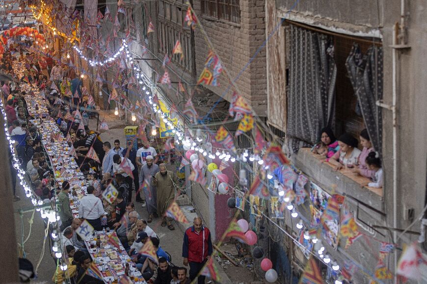 Muslims gather along a street-long table to break their Ramadan fast together in a mass "iftar" meal on the 15th day of the Muslim holy month, in the Matariya suburb of Egypt's capital Cairo on April 16, 2022