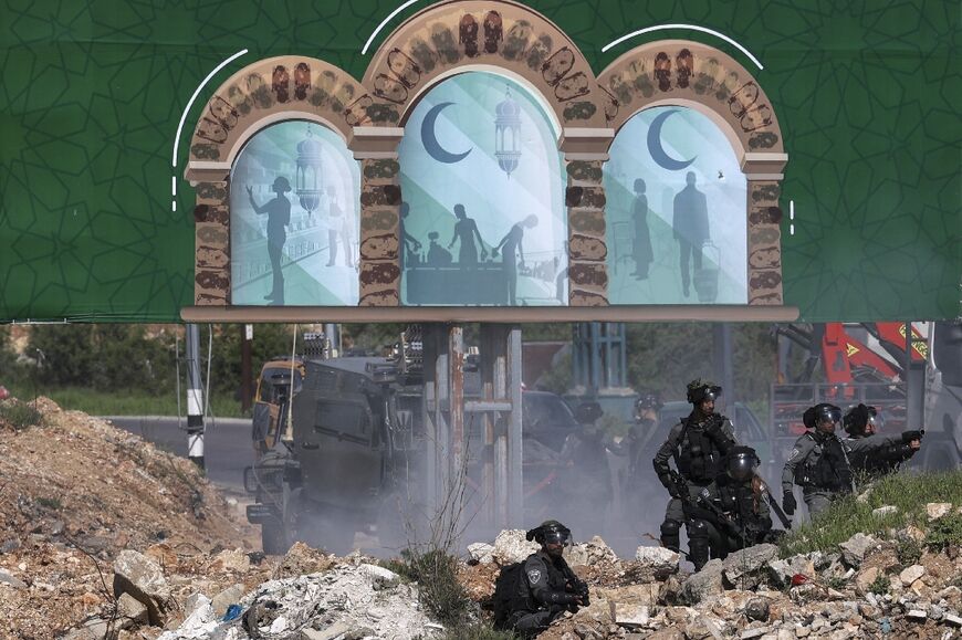 Israeli security forces take position under a poster celebrating the Muslim holy month of Ramadan at the northern entrance to Ramallah